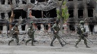 Sejumlah tentara Rusia berjalan diantara puing bangunan yang hancur di pabrik baja Azovstal. REUTERS/Alexander Ermochenko