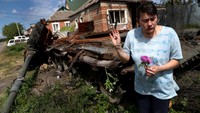 Gempuran invasi Rusia di kawasan Mala Rohan membuat seorang warga bernama Tamara memberi isyarat saat ia mengambil setangkai bunga di sebelah tank yang rusak. REUTERS/Ivan Alvarado