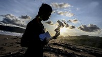 Seorang jurnalis melihat botol sampah plastik produksi luar negeri yang terbawa arus di bibir pantai selatan, kawasan Taman Nasional Ujung Kulon (TNUK), Pandeglang, Banten, Senin (16/5/2022).