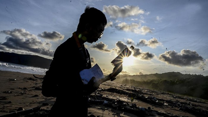 SAMPAH PLASTIK DI PANTAI TNUK Seorang jurnalis memperlihatkan botol sampah plastik produksi luar negeri yang terbawa arus di bibir pantai selatan, kawasan Taman Nasional Ujung Kulon (TNUK), Pandeglang, Banten, Senin (16/5/2022). Banyaknya sampah plastik di kawasan tersebut diperkirakan dapat menyebabkan perubahan perilaku satwa di wilayah tersebut salah satunya badak jawa yang disinyalir tidak lagi terlihat di muara dekat pantai selatan. ANTARA FOTO/Muhammad Adimaja/tom.