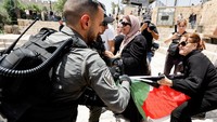 Seorang polisi Israel menarik bendera Palestina dari seorang warga di tengah bentrokan yang terjadi di dekat gerbang Damaskus ke kawasan kota tua Yerusalem, Minggu (29/5/2022). REUTERS/Ammar Awad.