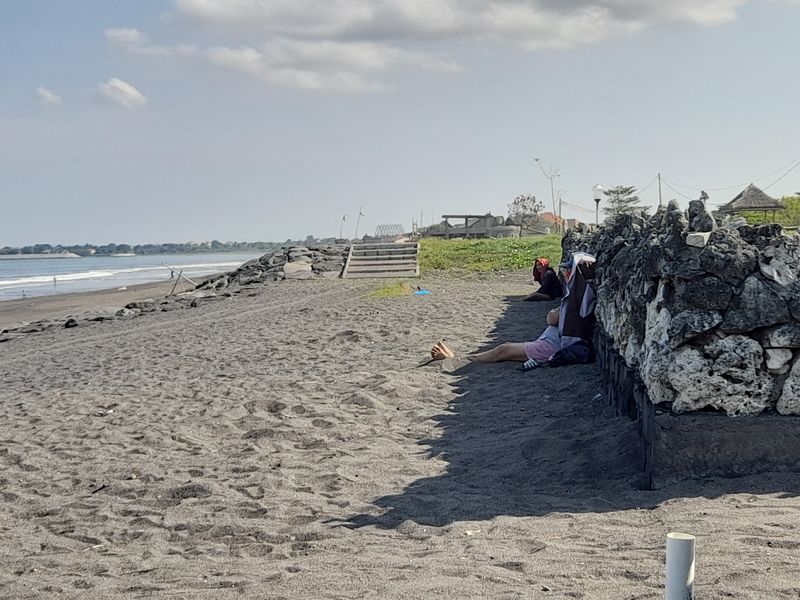 Warga di sekitar Pantai Lembeng, Desa Adat Ketewel, Gianyar melakukan terapi tradisional dengan menimbun kakinya dengan pasir pantai, Minggu (29/5/2022).