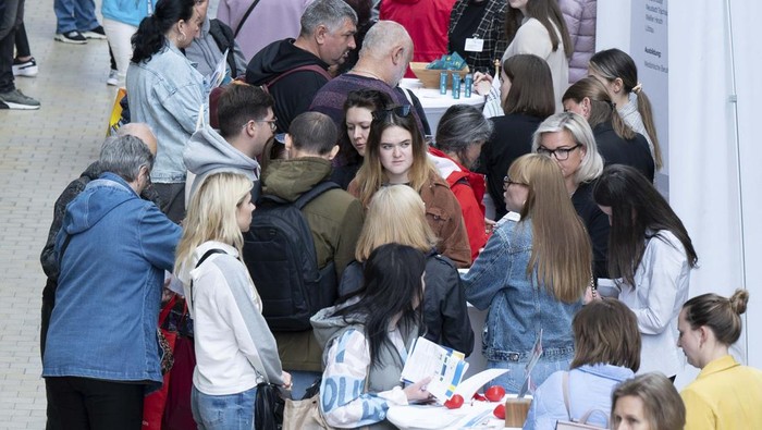 People visit a job fair for refugees from Ukraine in the foyer of the World Trade Center in Dresden, Germany, Monday, May 30, 2022. More than 30 companies present themselves at the fair in cooperation with the Federal Employment Agency. (Sebastian Kahnert/dpa via AP)