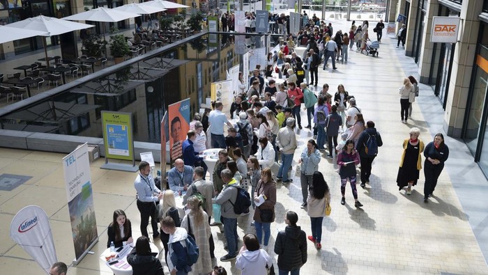 People visit a job fair for refugees from Ukraine in the foyer of the World Trade Center in Dresden, Germany, Monday, May 30, 2022. More than 30 companies present themselves at the fair in cooperation with the Federal Employment Agency. (Sebastian Kahnert/dpa via AP)