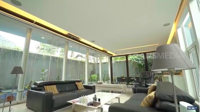 Ruang keluarga dikelilingi kaca-kaca yang membiarkan cahaya alami masuk dan menciptakan kesan lapang. Area tersebut langsung bersebelahan dengan kolam renang yang menyumbangkan kesan teduh.  (Foto: YouTube/Trans7 Official)