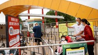 Sejumlah pengunjung memindai kode QR kesehatan sebelum memasuki Sun Park, Minggu, (29/5/2022). Otoritas Beijing melonggarkan beberapa pembatasan terkait Covid-19, salah satunya membuka kembali taman bermain.