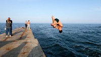 Beberapa warga terlihat melompat gaya bebas di tanggul Laut Hitam.