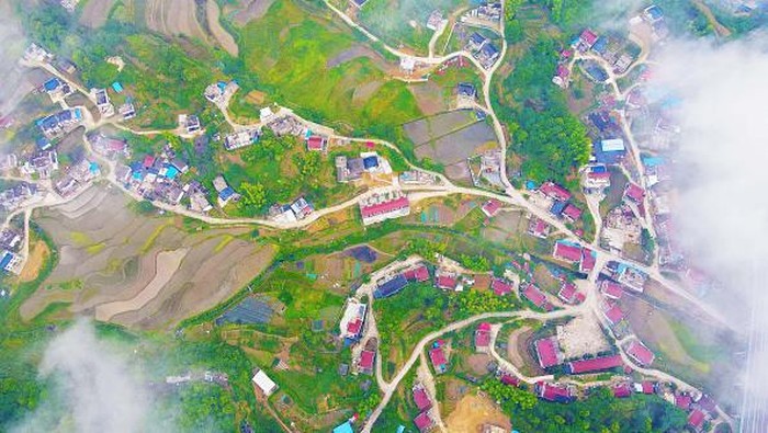 ANQING, CHINA - MAY 31, 2022 - Aerial photo taken on May 31, 2022 shows muchong community in Tiantang Town, Yuexi County, Anqing City, East China's Anhui Province. The highway connecting the village and the castle peak, the stacked terraced fields and the well-arranged residential buildings complement each other. In recent years, Anqing city has strengthened the construction, operation and management of rural roads, carried out quality improvement projects as a whole, and built a reasonable layout and smooth road network. Highways run through the beautiful mountains and rivers, facilitating villagers' travel, boosting industrial development and providing a strong guarantee for people to increase their income and get rich. (Photo credit should read CFOTO/Future Publishing via Getty Images)