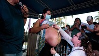 Seorang juri mengukur besar perut ibu hamil yang mengikuti kontes La Madre Panza.