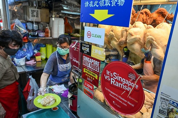 A vendor prepares a plate of chicken rice at a hawker centre in Singapore on May 31, 2022. - Singapore imports a third of its chicken supply from Malaysia, which will halt the export of 3.6 million chickens a month from June 1 onwards, amid surging prices and supply concerns. (Photo by Roslan RAHMAN / AFP) (Photo by ROSLAN RAHMAN/AFP via Getty Images)