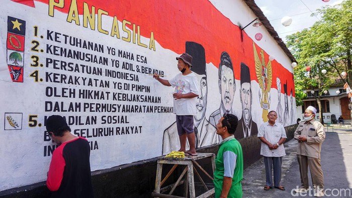 Warga menyelesaikan proses pengecatan mural bertemakan Pancasila dengan media tembok rumah di jalan masuk Dusun Karangwatu, Pucungrejo, Muntilan, Magelang, Jawa Tengah, Selasa (31/5/2022). Pembuatan mural tersebut dalam rangka memperingati hari lahirnya Pancasila pada tanggal 1 Juni.