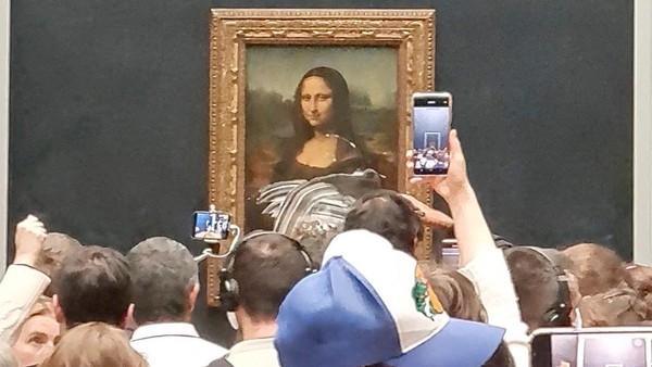 Petugas keamanan museum pun langsung membawa pria berwig tersebut keluar. Pengunjung yang ada di hari libur itu tak henti-hentinya mengabadikan momen tak biasa itu. Untuk diketahui, lukisan Mona Lisa adalah satu-satunya ikon dari karya Leonardo da Vinci. Di Museum Louvre, lukisan itu punya daya tarik tersendiri sampai sukses menggaet puluhan juta pengunjung dari seluruh dunia. Mona Lisa dibuat dalam rentang tahun 1503 dan 1519. Ada banyak sumber yang menyebutkan mengenai tokoh dalam lukisan maupun alasan di balik da Vinci membuatnya. Twitter/@klevisl007/via REUTERS.