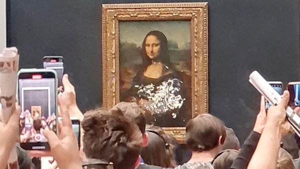 Sejumlah pengunjung memotret dan merekam lukisan legendaris karya Leonardo Da Vinci, Mona Lisa yang dilempari kue oleh seorang pria di Museum Louvre, Paris, Minggu (29/5/2022). Twitter/@klevisl007/via REUTERS.