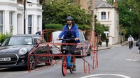 Seorang pesepeda membuat kerangka mobil dari besi kemudian dibawa menggunakan sepeda keliling kota London, Rabu (11/5/2022).