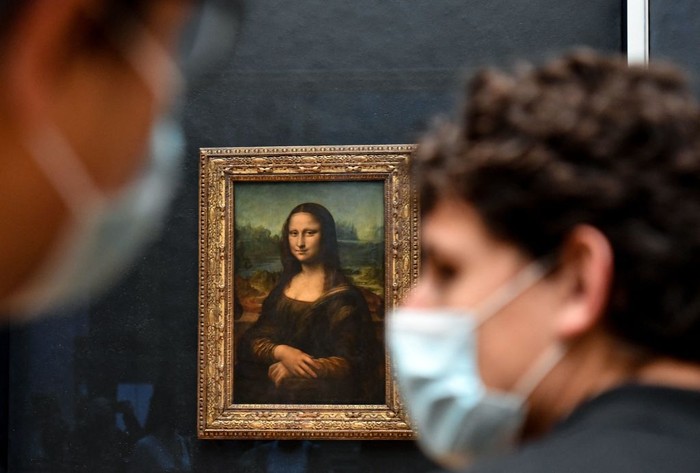 PARIS, FRANCE - MAY 19: Visitors observe the painting La Joconde The Mona Lisa by Italian artist Leonardo Da Vinci on display in a gallery at Louvre on May 19, 2021 in Paris, France. The country is taking steps to ease the lockdown measures that President Emmanuel Macron announced on April 29, allowing all the museums and non-essential shops and cultural venues to open and rolling back the curfew to 9pm. The cafe and restaurant terraces can also open to 50% capacity. France is reporting a seven-day average of around 14,000 new Covid-19 cases. (Photo by Marc Piasecki/Getty Images)