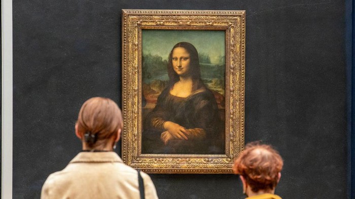 PARIS, FRANCE - MAY 19: Visitors observe the painting La Joconde The Mona Lisa by Italian artist Leonardo Da Vinci on display in a gallery at Louvre on May 19, 2021 in Paris, France. The country is taking steps to ease the lockdown measures that President Emmanuel Macron announced on April 29, allowing all the museums and non-essential shops and cultural venues to open and rolling back the curfew to 9pm. The cafe and restaurant terraces can also open to 50% capacity. France is reporting a seven-day average of around 14,000 new Covid-19 cases. (Photo by Marc Piasecki/Getty Images)