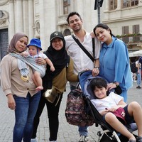 Jika pengasuh Rayyanza, Lala tampil dengan topi dan tas bermerek, Rini justru terlihat berpenampilan sederhana. Sambil menggendong Rayyanza, Rini terlihat hanya mengenakan kaos lengan panjang berwarna coklat dengan celana jeans berwarna biru. Penampilannya itu dilengkapi dengan hijab berwarna coklat. Foto: Instagram