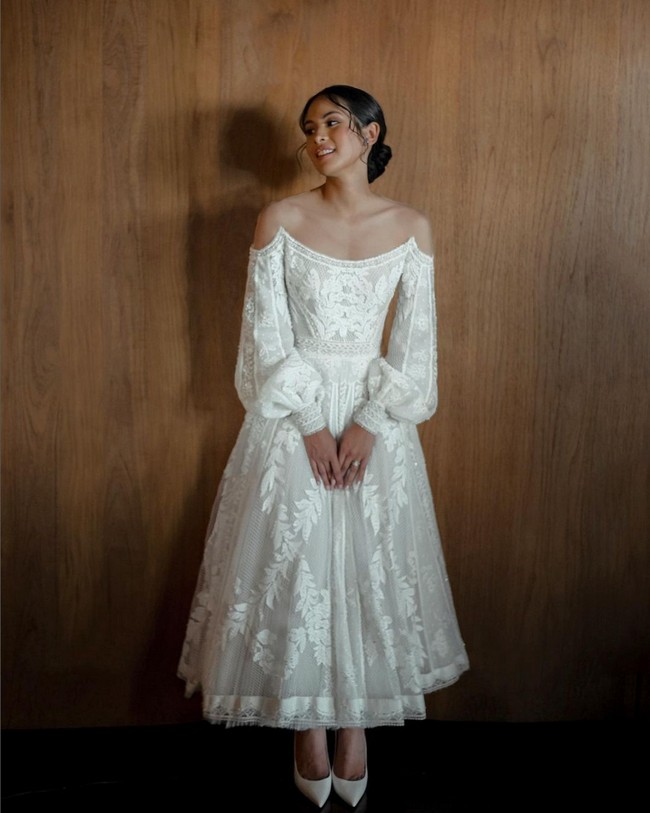 Maudy Ayunda tampil cantik dan anggun berbalut gaun pengantin karya desainer Hian Tjen. Gaun berbahan lace ini tampak unik dengan ilusi off-the-shoulder dan lengan bervolume. Foto: Instagram/@maudyayunda @iluminen
