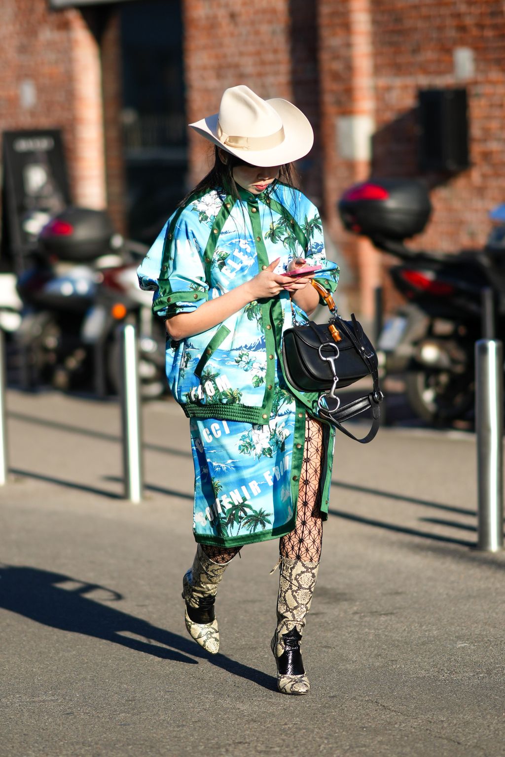 Tren Topi Koboi MILAN, ITALY - FEBRUARY 25: A guest wears a white latte felt hat, a pale blue / white / green print pattern oversized jacket, matching pale blue / white / green print pattern shorts, a black shiny leather handbag from Gucci, black fishnet print pattern tights, beige and black shiny leather snake print pattern pointed block heels knees boots, outside the Gucci fashion show, during the Milan Fashion Week Fall/Winter 2022/2023 on February 25, 2022 in Milan, Italy. (Photo by Edward Berthelot/Getty Images)