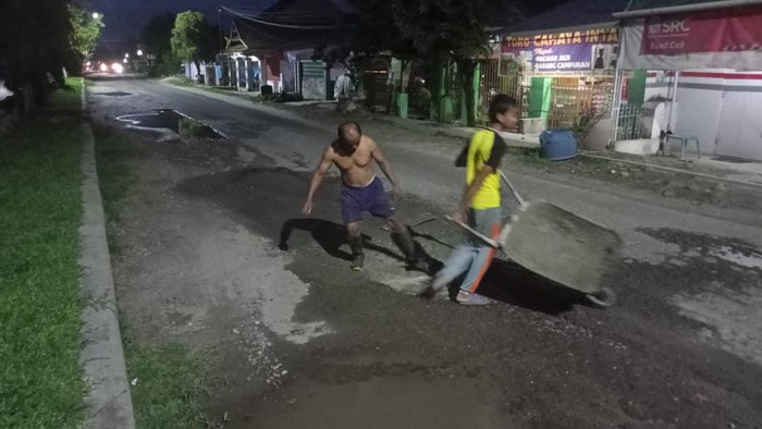 Warga Lutra memperbaiki jalan rusak.