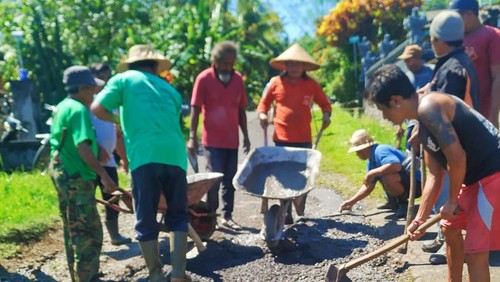 Warga melakukan penambalan secara swadaya pada jalan berlubang di Desa Gumbrih, Kecamatan Pekutatan, Kabupaten Jembrana Bali, Minggu (30/5/2022)