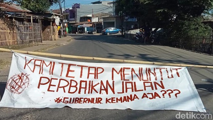 Warga memblokade jalan dan memasang spanduk protes karena kerusakan Jalan Antang Raya tak kunjung ditangani
