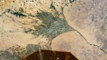 Foto pertanian di Turkmenistan yang dikepung gumuk pasir. Di bawah foto ada yang ikut terpotret adalah panel surya milik roket Cygnus NG-15 yang lagi mampir ke ISS. Foto: NASA