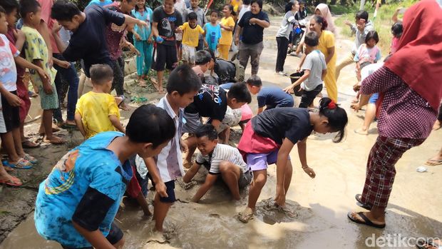 Keseruan bocah-bocah di Asahan menangkap ikan lele di kubangan jalan rusak.