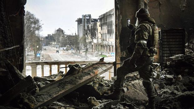 Seorang tentara Rusia berpatroli di teater drama Mariupol yang dibom 16 Maret lalu di Mariupol, Selasa (12/4/2022). (Photo by Alexander NEMENOV / AFP)