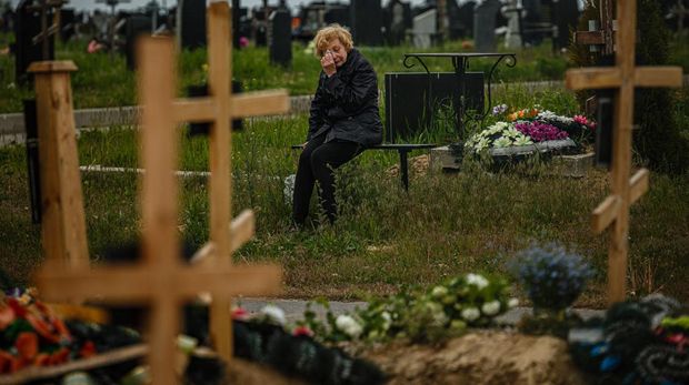 TOPSHOT - A woman mourns while visiting the grave of Stanislav Hvostov, 22, a Ukrainian serviceman killed during the Russian invasion of Ukraine, in the military section of the Kharkiv cemetery number 18 in Bezlioudivka, eastern Ukraine on May 21, 2022. (Photo by Dimitar DILKOFF / AFP) (Photo by DIMITAR DILKOFF/AFP via Getty Images)