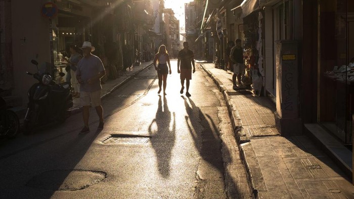 1241047769 A man puts the newspaper for protection from the sun at Ermou street in the center if Athens, Greece on June 1, 2022. Greece was in high temperatures today. (Photo by Nikolas Kokovlis/NurPhoto via Getty Images)