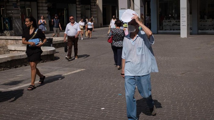 1241047769 A man puts the newspaper for protection from the sun at Ermou street in the center if Athens, Greece on June 1, 2022. Greece was in high temperatures today. (Photo by Nikolas Kokovlis/NurPhoto via Getty Images)