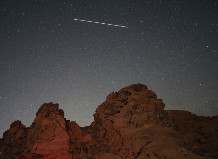 VALLEY OF FIRE STATE PARK, NEVADA - MAY 30: A meteor streaks above sandstone formations as the Earth passes through the debris trails of a broken comet called 73P/Schwassmann-Wachmann, or SW3, producing a never-before-seen meteor shower called the tau Herculids on May 30, 2022 in the Valley of Fire State Park, Nevada. SW3, which orbits the sun every 5.4 years, crumbled in 1995, resulting in large fragments spewing material that the Earth is passing through for the first time. (Photo by Ethan Miller/Getty Images)