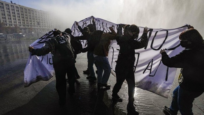 Demo Mahasiswa di Chile Berakhir Kisruh Hingga Bakar Bus A protester launches orange smoke during a student protest outside La Moneda presidential palace in Santiago, Chile, Wednesday, June 1, 2022. Students are protesting on the day Chilean President Gabriel Boric gives his first annual address as president, while continuing to demand free, non-sexist education as well as fair transportation prices, more food vouchers and the cancelation of student debt. (AP Photo/Esteban Felix)