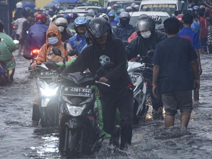 Sejumlah sepeda motor mendorong kendaraanya yang mogok saat melintasi genangan air di Jalan Kaliabang, Bekasi, Jawa Barat, Kamis (2/6/2022). Genangan air usai hujan dengan ketinggian 20 cm hingga 40 cm terjadi karena kualitas drainase yang buruk dan mengakibatkan kendaraan sepeda motor pengguna jalan mogok. ANTARA FOTO. Fakhri Hermansyah/hp.