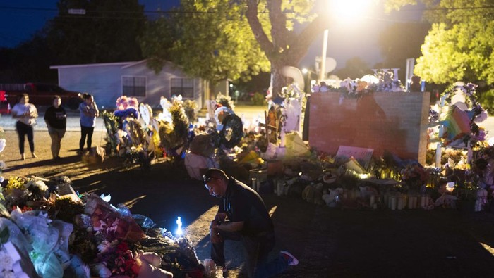 A man kneels in front of a mound of flowers at a memorial at Robb Elementary School in Uvalde, Texas, Wednesday, June 1, 2022, to pay his respects to the victims killed in last week's school shooting. (AP Photo/Jae C. Hong)