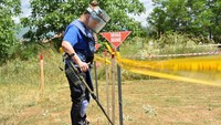Seorang wanita menggunakan pelindung tubuh dan detektor ranjau dalam pelatihan menjinakkan ranjau darat, di Peja, Kosovo, (31/5/2022).