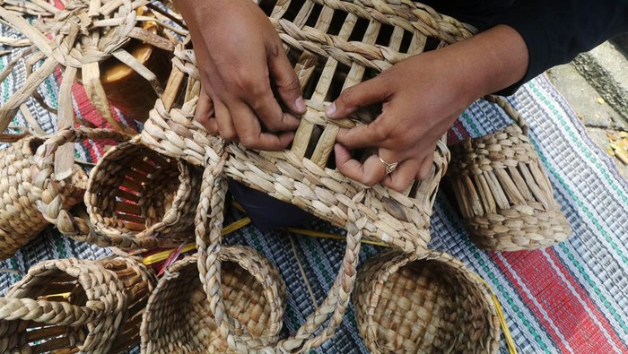 Peserta menganyam batang tanaman enceng gondok kering saat pelatihan pembuatan kerajinan di Sumber Kembangan, Kediri, Jawa Timur, Sabtu (4/6/2022). Pelatihan yang diikuti oleh para ibu rumah tangga tersebut guna memberikan wawasan tentang pembuatan kerajinan berbahan baku tanaman enceng gondok kering berupa tas, vas bunga, dan hiasan rumah sehingga dapat menjadi usaha sampingan ramah lingkungan sekaligus membantu perekonomian keluarga. ANTARA FOTO/Prasetia Fauzani/nym.