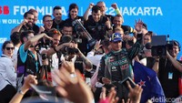 Juara Formula E diberi piala kemudian merayakan di atas panggung.