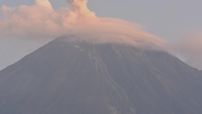 ASAP GUNUNG SEMERU Warga menaiki sepeda motor dengan latar belakang Gunung Semeru mengeluarkan asap yang tampak dari Desa Supiturang, Pronojiwo, Lumajang, Jawa Timur, Minggu (5/6/2022). Pusat Vulkanologi dan Mitigasi Bencana Geologi (PVMBG) menyatakan Gunung Semeru masih berstatus level tiga atau siaga dan mengimbau masyarakat untuk tidak beraktivitas pada jarak 500 meter dari tepi sungai (sempadan sungai) di sepanjang Curah Kobokan atau aliran lahar hingga jarak 17 km dari puncak karena berpotensi terdampak perluasan awan panas. ANTARA FOTO/Seno/tom.