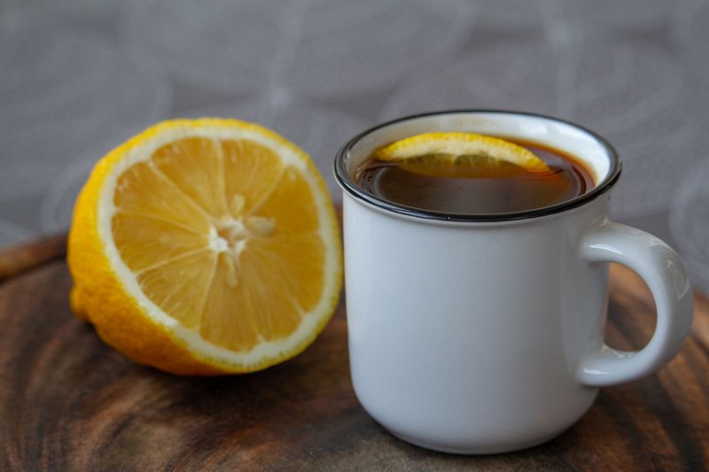 Cup of black coffee with a slice of lemon on a gray tablecloth, selective focus