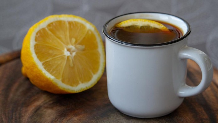 Cup of black coffee with a slice of lemon on a grey tablecloth, selective focus