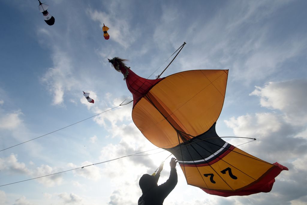 Peserta menarik tali layang-layang saat mengikuti perlombaan dalam Dwi Tunggal Melesat Kite Festival di persawahan Nyalin, Desa Pedungan, Denpasar, Bali, Sabtu (4/6/2022). Kegiatan yang digelar untuk pelestarian permainan tradisional Bali tersebut kembali diselenggarakan setelah sempat ditiadakan selama dua tahun akibat pandemi COVID-19. ANTARA FOTO/Nyoman Hendra Wibowo/tom.