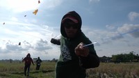 Peserta menarik tali layang-layang saat mengikuti perlombaan dalam Dwi Tunggal Melesat Kite Festival di persawahan Nyalin, Desa Pedungan, Denpasar, Bali.