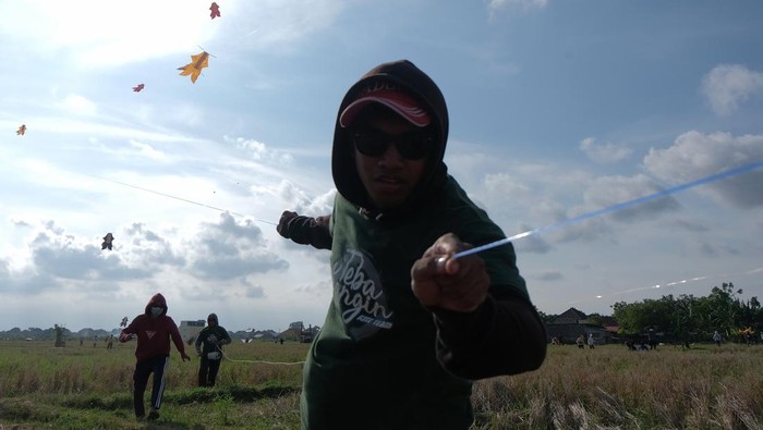 Peserta menarik tali layang-layang saat mengikuti perlombaan dalam Dwi Tunggal Melesat Kite Festival di persawahan Nyalin, Desa Pedungan, Denpasar, Bali, Sabtu (4/6/2022). Kegiatan yang digelar untuk pelestarian permainan tradisional Bali tersebut kembali diselenggarakan setelah sempat ditiadakan selama dua tahun akibat pandemi COVID-19. ANTARA FOTO/Nyoman Hendra Wibowo/tom.