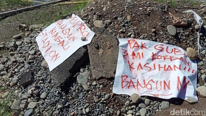 Poster kritikan di kubangan proyek Stadion Mattoanging yang telah menelan korban jiwa.