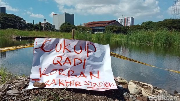 Poster kritikan di kubangan proyek Stadion Mattoanging yang telah menelan korban jiwa.