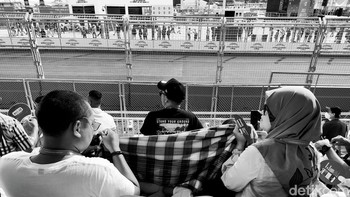 Orang tua melindungi anak tercinta yang kepanasan dengan sarung. Foto: Adi Fida Rahman/detikINET