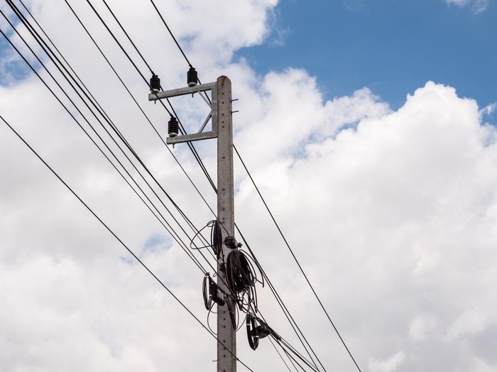 Small electric pole with the telephone cable under the clear blue sky.