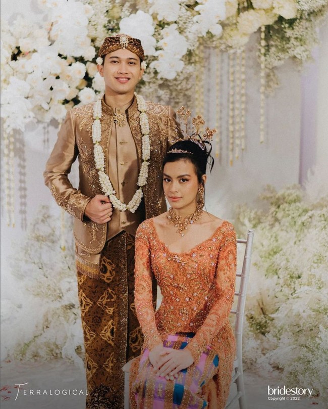Dekorasi putih tampak kontras dengan busana Eva Celia dan Demas Narawangsa yang merupakan perpaduan oranye, emas dan cokelat. Keindahan dekorasi pernikahan merupakan karya dari Yu Cien Lotus Design. Foto: Instagram/@thebridestory & @terralogical